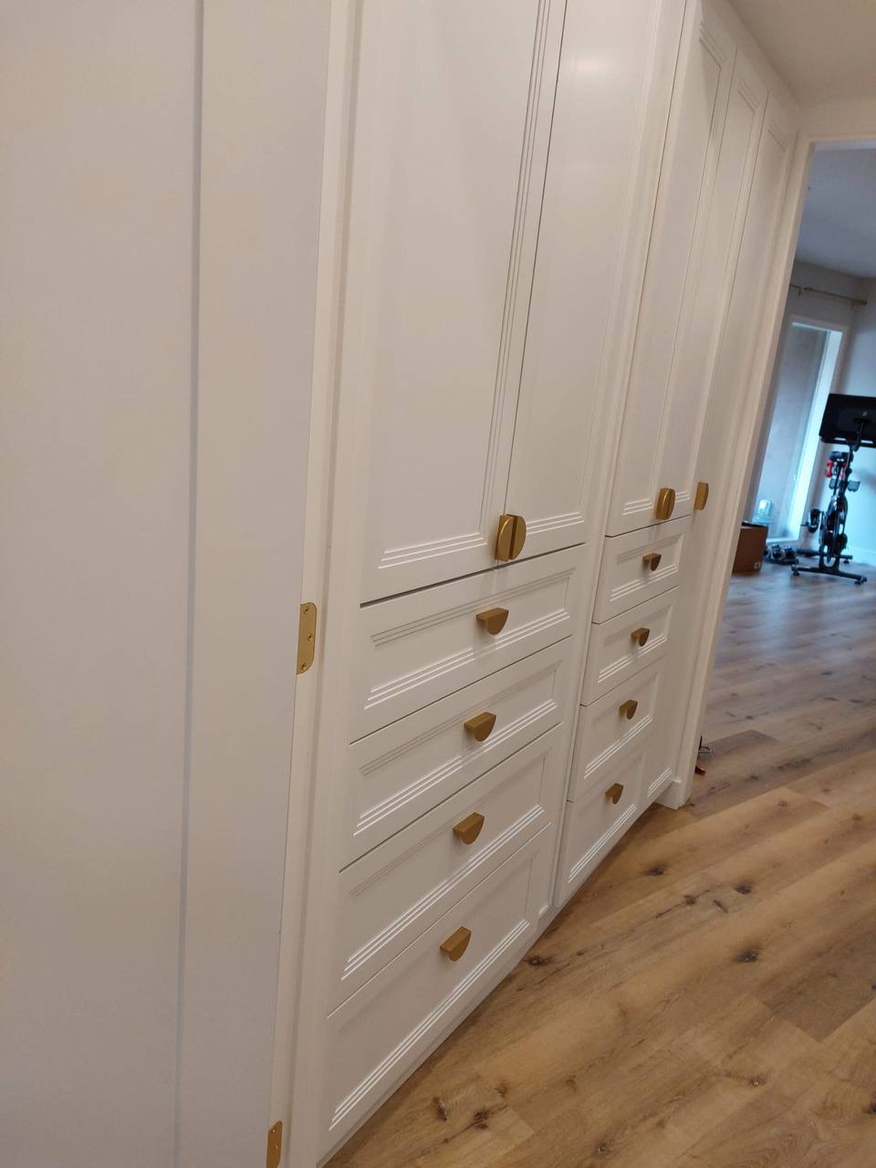 Custom white hallway built-in storage cabinets with fluted picture-frame trim and brass hardware in Glendale CA