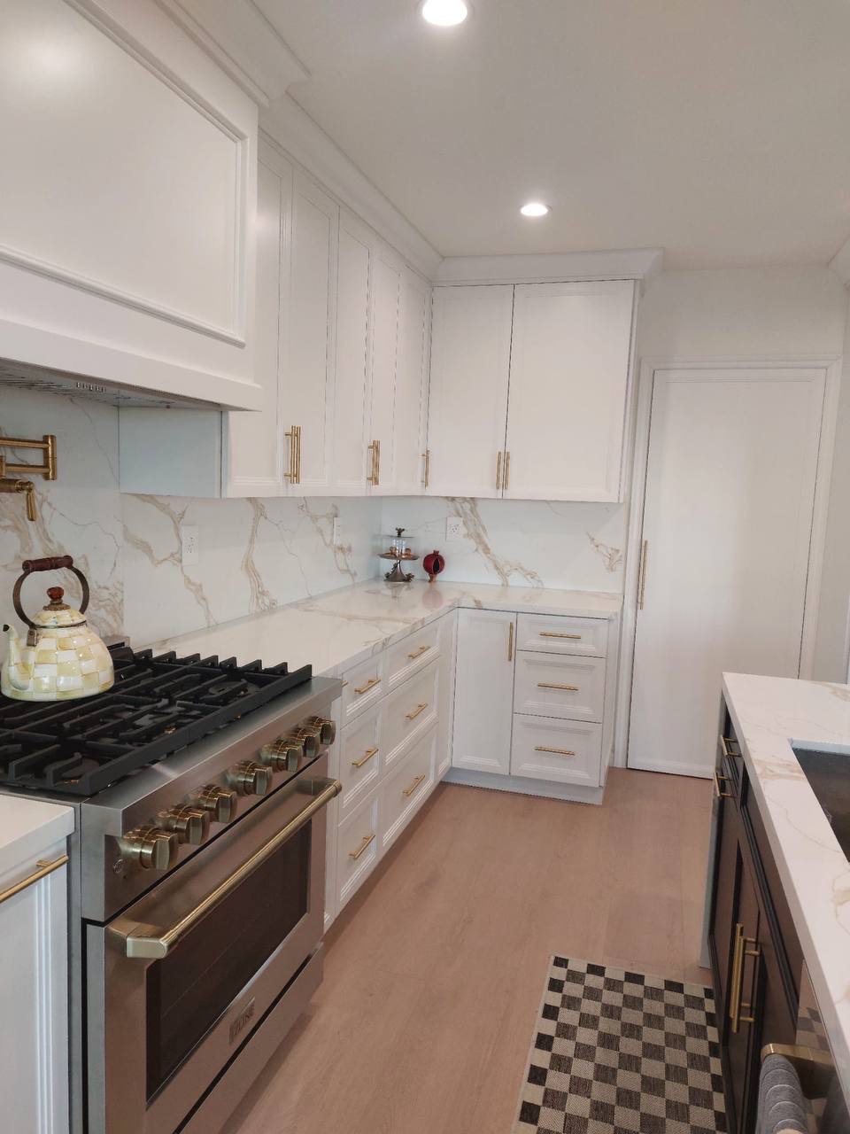 Custom white shaker kitchen with framed Viking range, brass pot filler and calacatta backsplash in Glendale CA