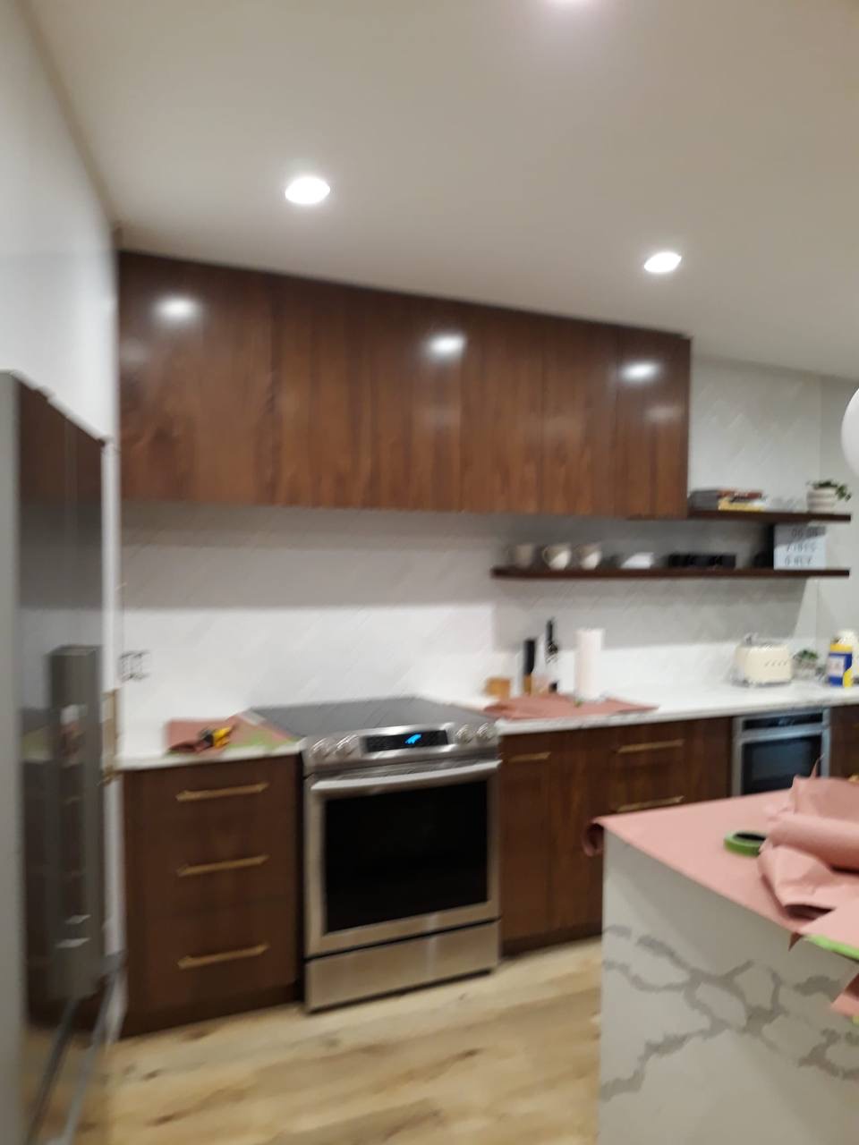 Custom walnut kitchen range wall with floating shelves and quartz counters in a Glendale CA home