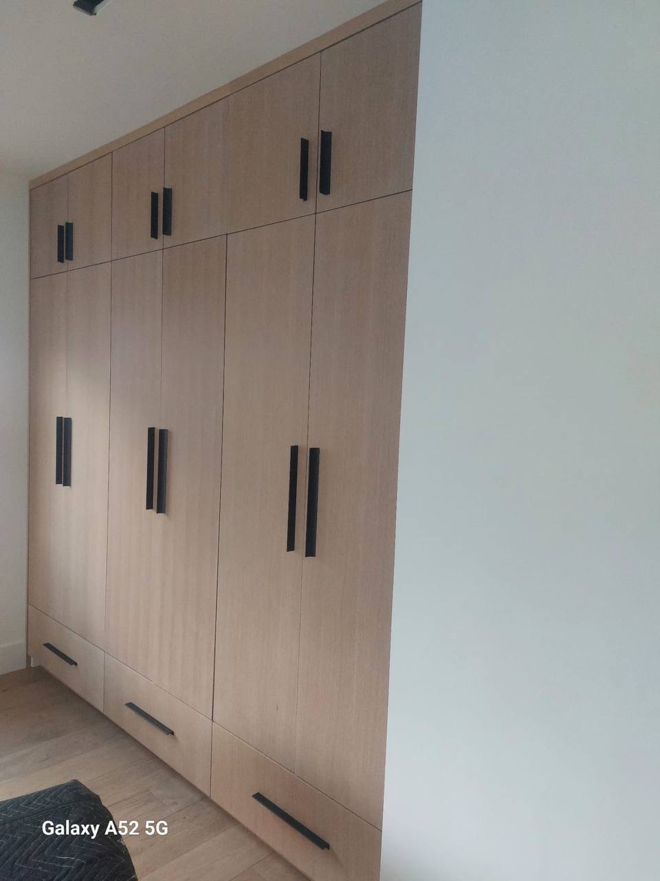 Custom white oak built-in bedroom wardrobe closet with long matte black pulls in Glendale CA