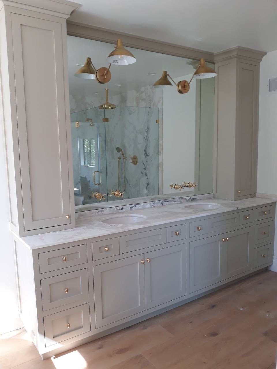 Custom gray double vanity with marble counter, flanking towers, and brass hardware in Glendale CA
