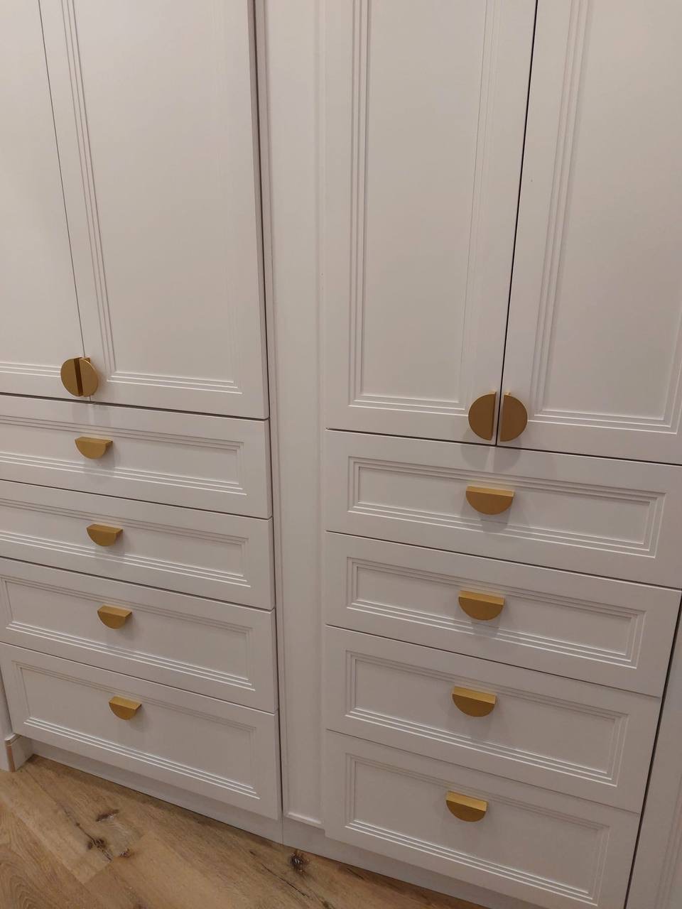 Custom white built-in wardrobe cabinets with picture-frame moulding and brass half-moon pulls in Glendale CA