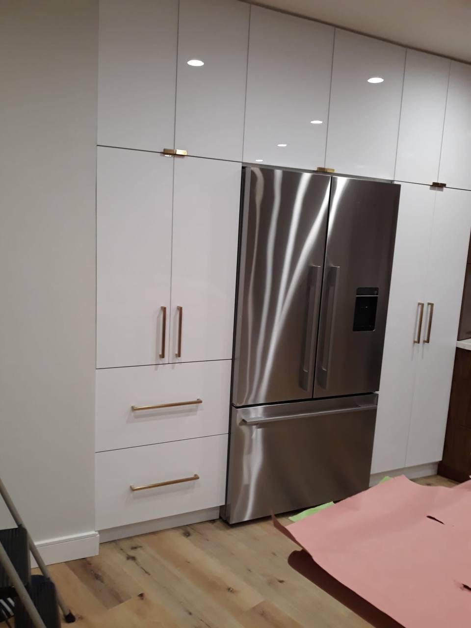 Custom white floor-to-ceiling pantry wall surrounding a stainless French-door fridge in Glendale CA