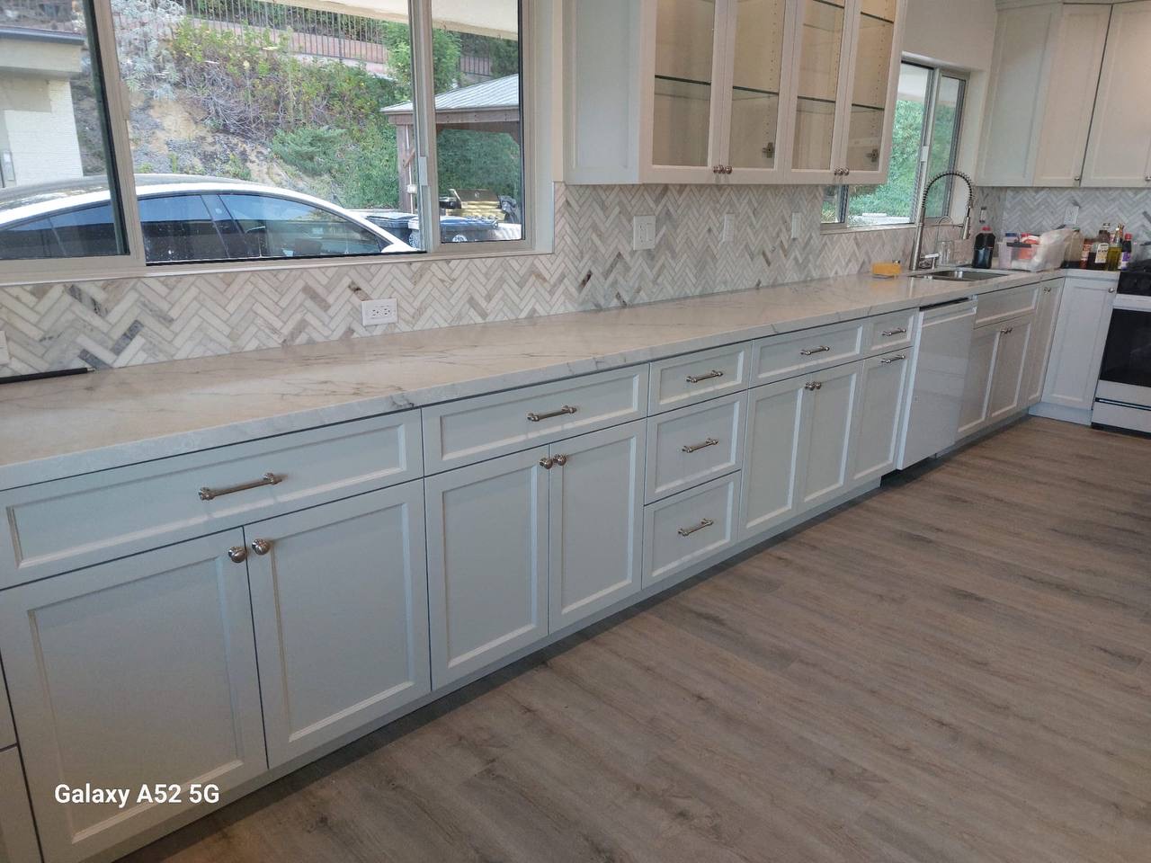 Custom white shaker kitchen cabinets with marble countertops and herringbone backsplash in a Glendale CA home