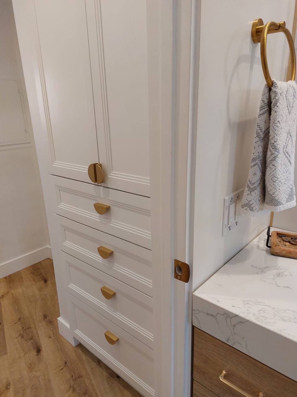 Custom white bathroom linen tower cabinet with picture-frame moulding and brass hardware in Glendale CA