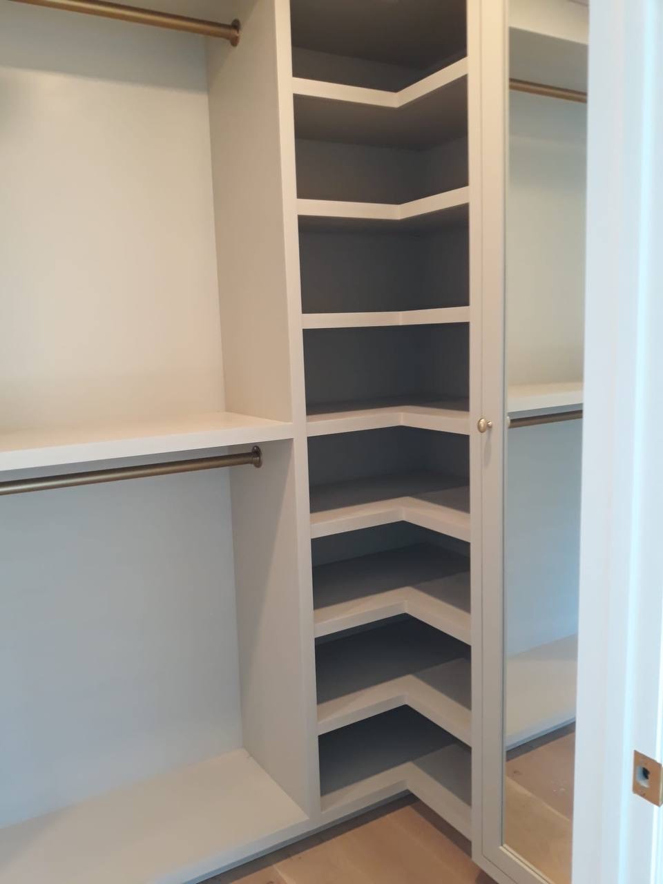 Custom white closet with corner shelving tower and brass hanging rods in Glendale CA