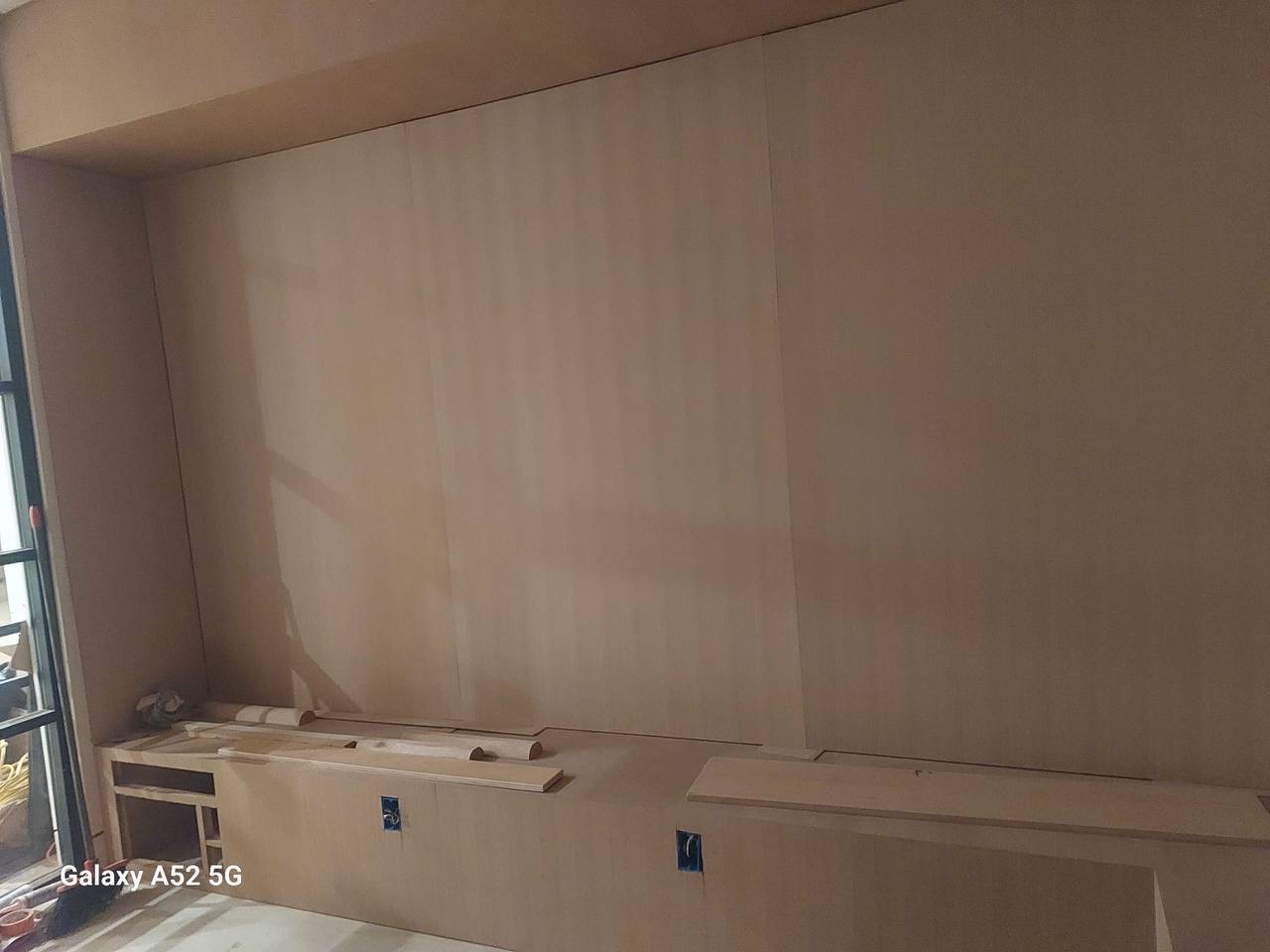 Custom paneled media wall built-in under construction in Glendale, showing fluted MDF panels and base cabinetry