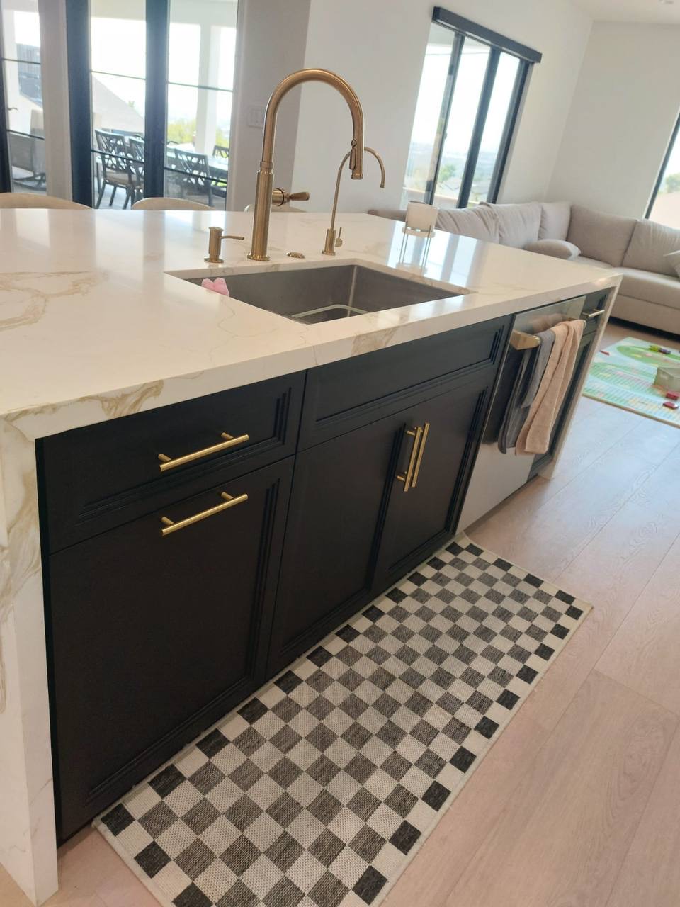 Custom black kitchen island with calacatta gold waterfall quartz, brass faucet and panel dishwasher in Glendale CA