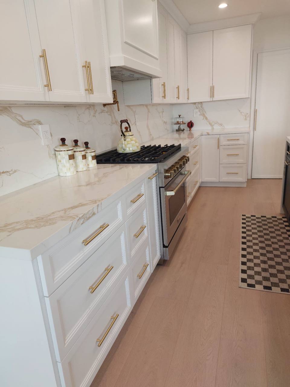 Custom white shaker kitchen range wall with built-up hood, calacatta slab backsplash and brass hardware in Glendale CA