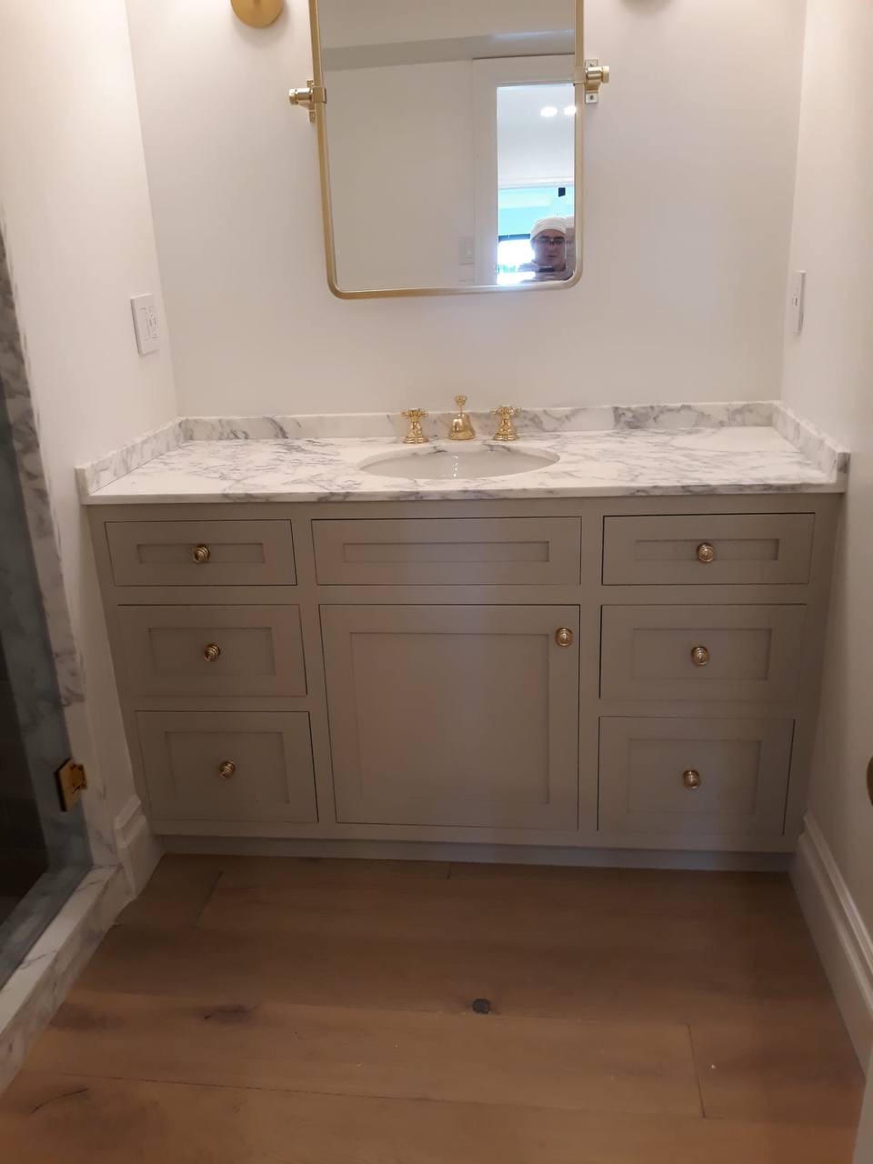 Custom gray powder room vanity with Carrara marble counter and brass knobs in Glendale CA