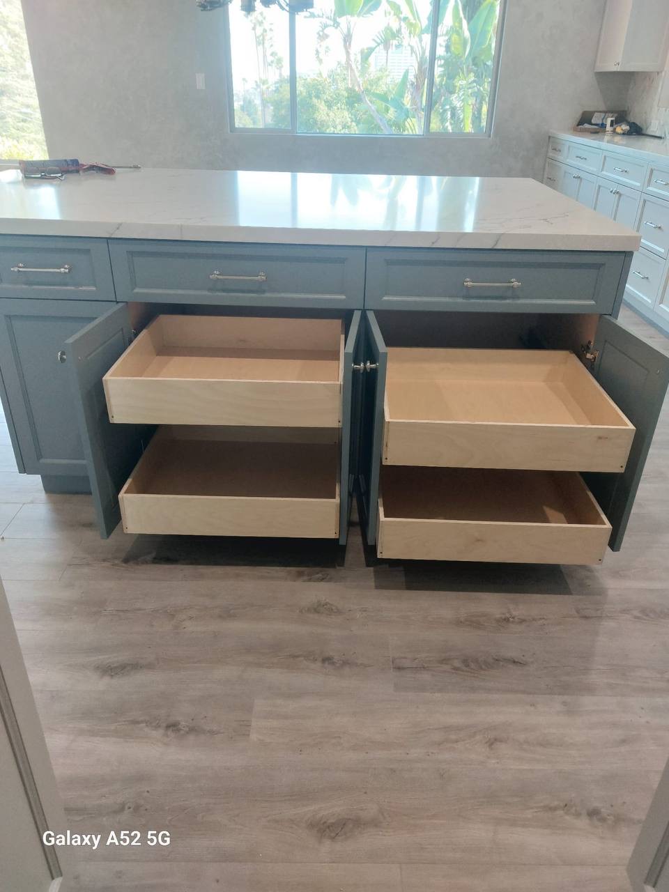 Custom sage green kitchen island with quartz counter and full-extension pull-out shelves in Glendale CA