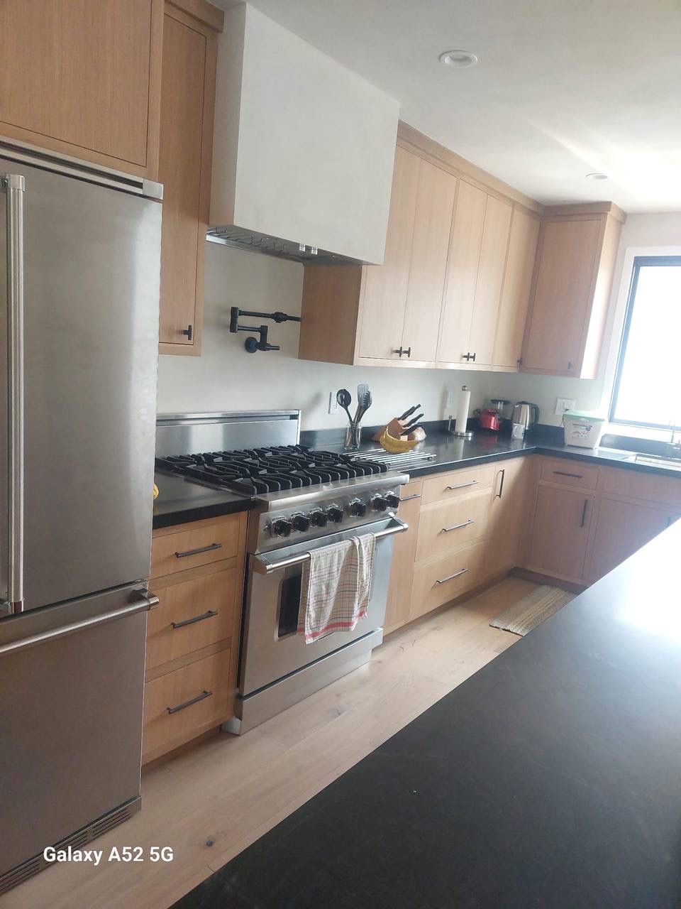 Custom white oak kitchen cabinetry with plaster range hood and wall-mounted pot filler in Glendale CA